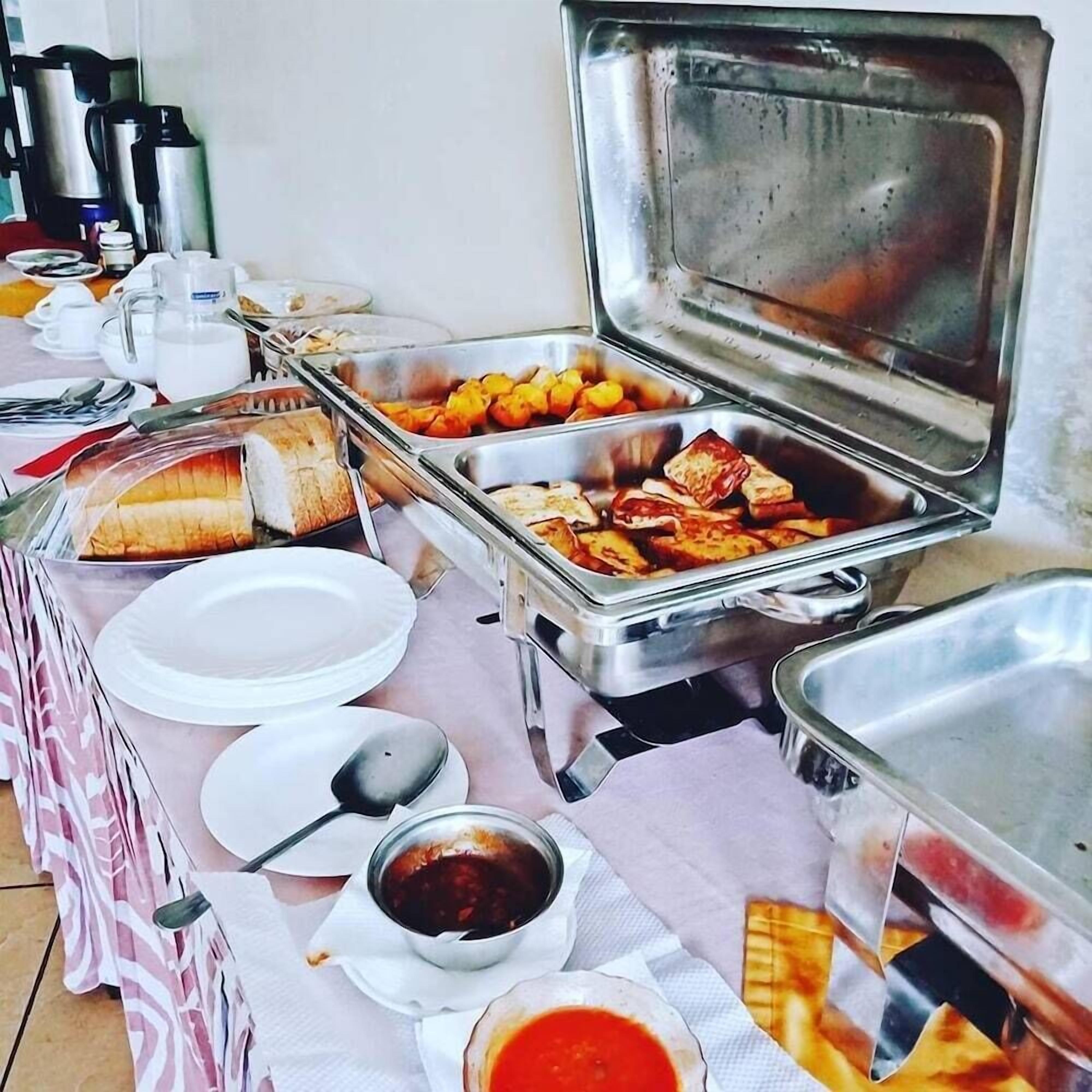A buffet setup with various food items, including bread, fruits, and sauces.