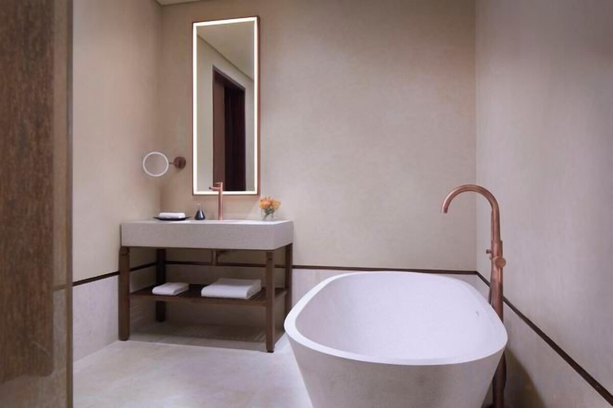 A modern bathroom with a freestanding bathtub, a vanity with a mirror, and a towel rack.