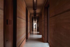 A corridor with wooden paneling and a person standing at the end. - Banyan Tree Alula (Al-'Ula)