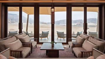 A room with a large window overlooking a desert landscape, furnished with sofas and a coffee table.