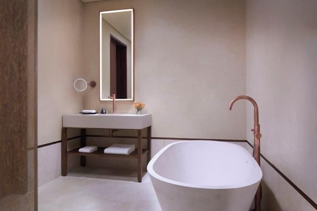 A bathroom with a freestanding bathtub, a vanity with a mirror, and a towel rack.