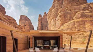 A modern outdoor lounge area with a view of rock formations, furnished with lounge chairs and a seating area.