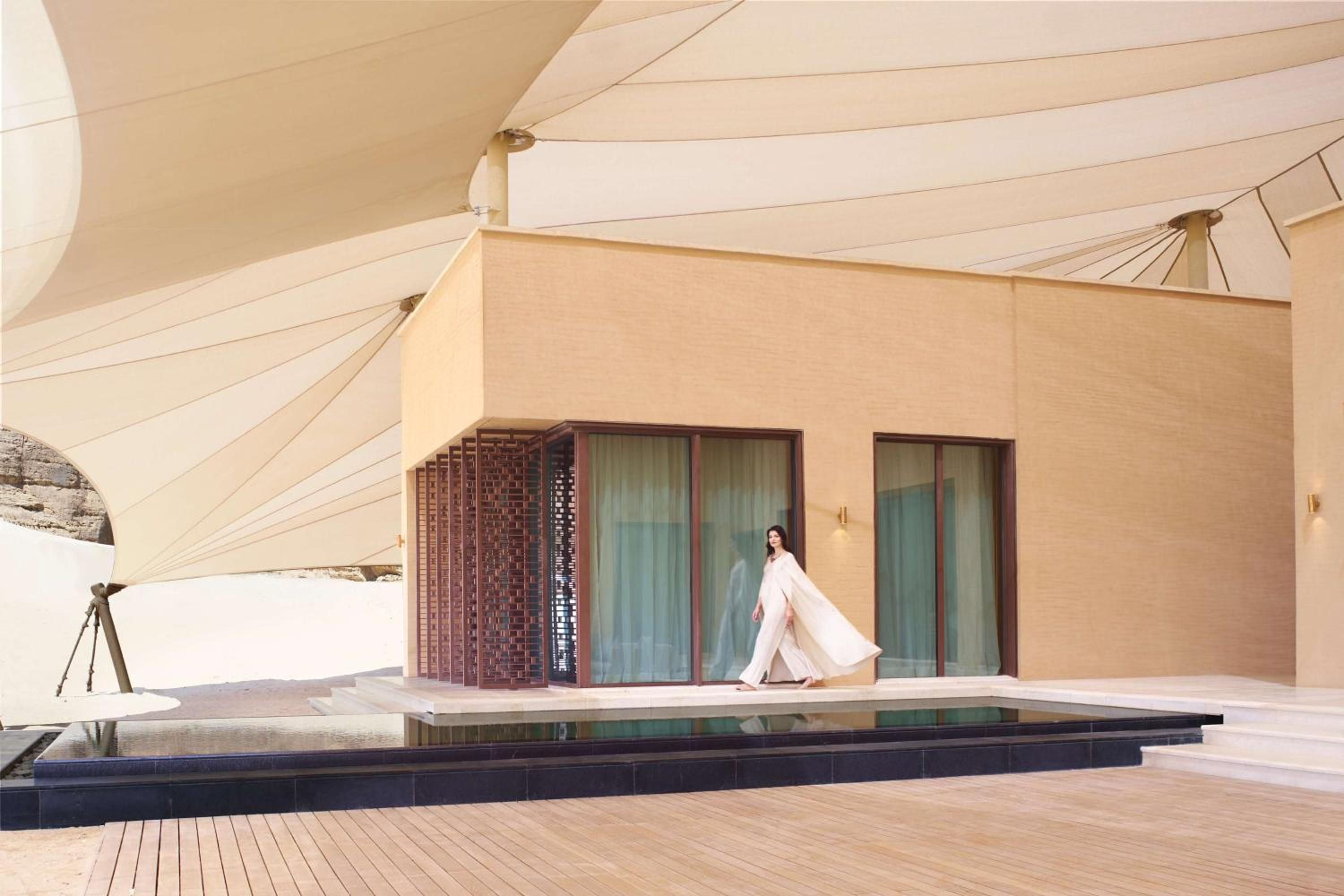 A modern building with a large overhang, a pool, and a person walking.
