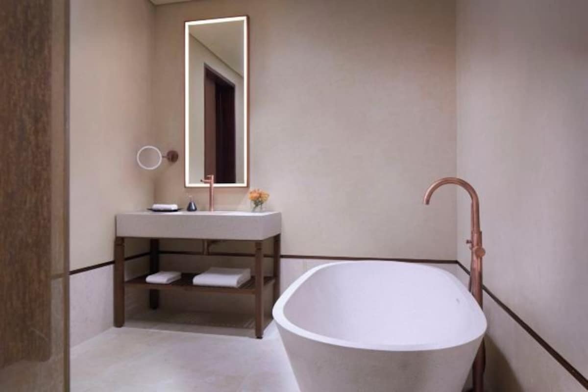 A bathroom with a freestanding bathtub, a vanity with a mirror, and a towel rack.