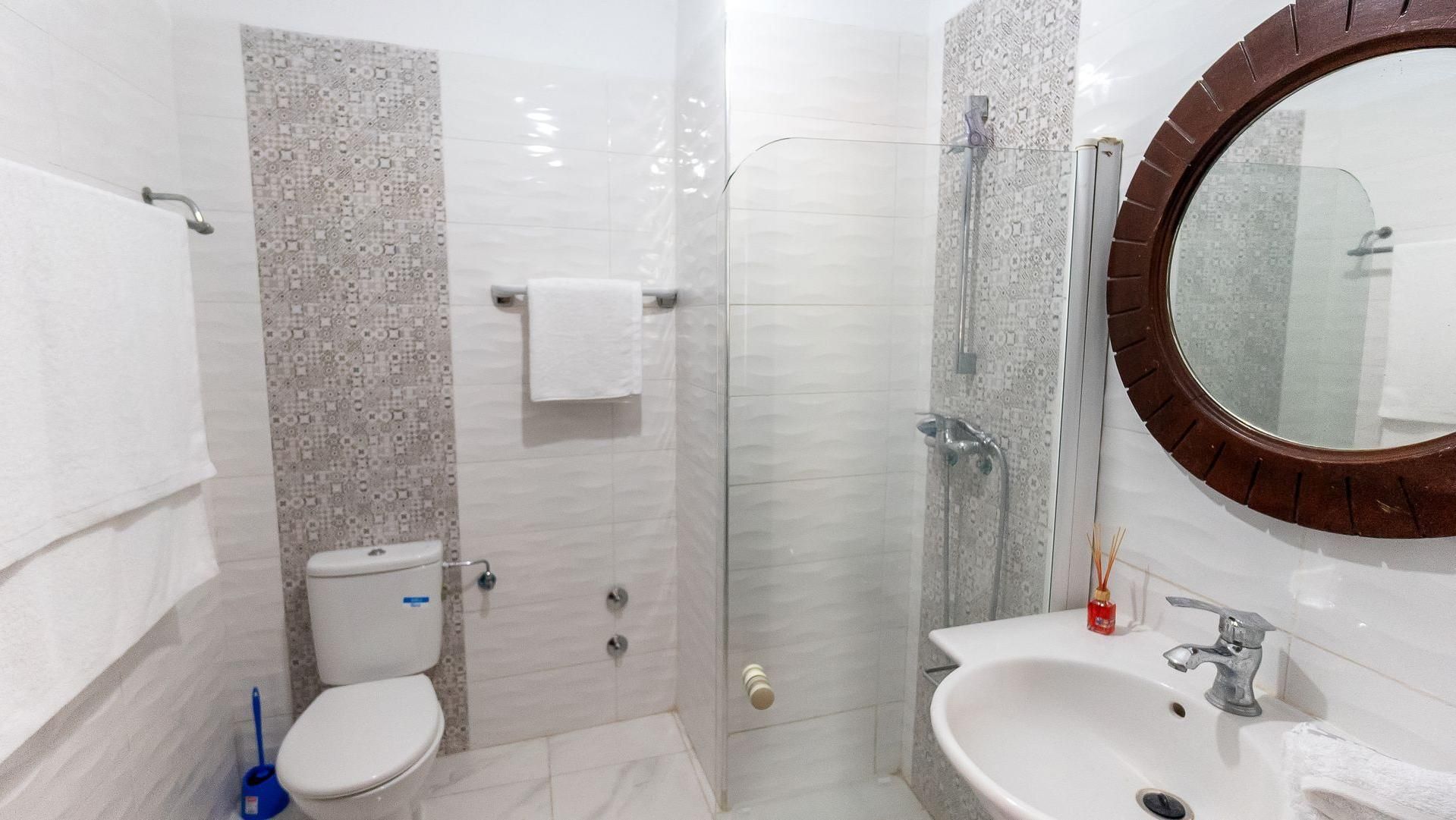 A bathroom with a toilet, a shower, and a sink.