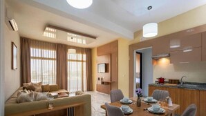 A modern hotel room with a sofa, dining table, and kitchen area. - Sables D'or Appart & Hotel (Agadir)