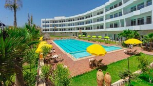 A hotel with a swimming pool, outdoor seating, and a well-maintained garden. - Sables D'or Appart & Hotel (Agadir)