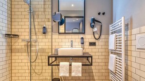 A modern bathroom with a glass-enclosed shower, a sink with a towel rack, and a toilet. - Nyce Hotel Ulm (Ulm)