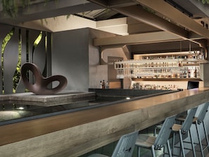 A modern bar area with a unique seating arrangement, a bar counter, and a variety of bottles and glasses. - The Chania Hotel (Chania)