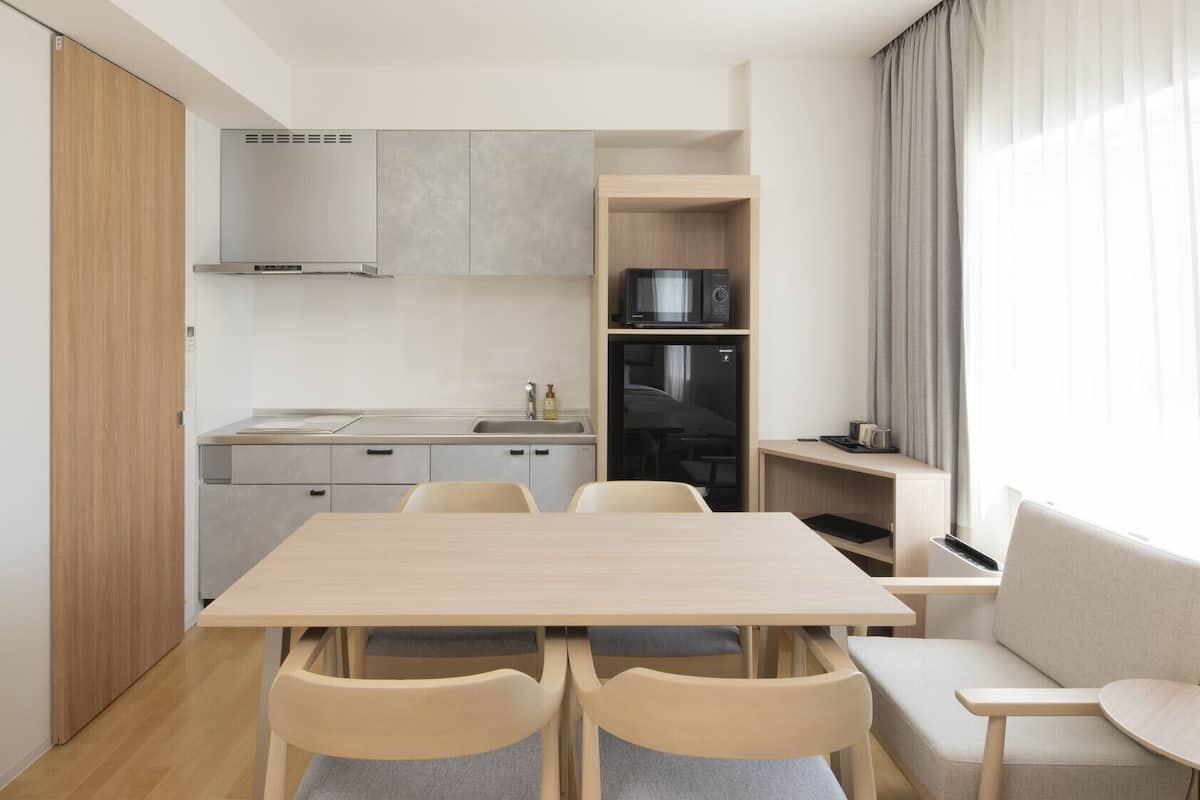 A compact kitchen with a dining area, including a table, chairs, and a built-in oven.