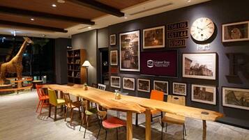 A dining area with a long wooden table and chairs, a giraffe statue, and framed pictures on the wall.