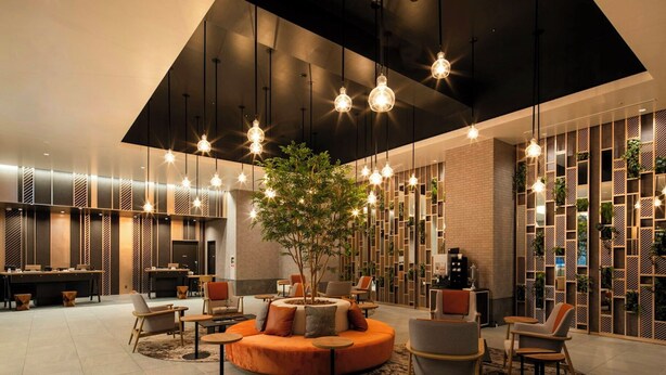 A modern lobby with a central seating area, hanging pendant lights, and a vertical garden wall. - La Gent Stay Shin Sapporo (Sapporo)
