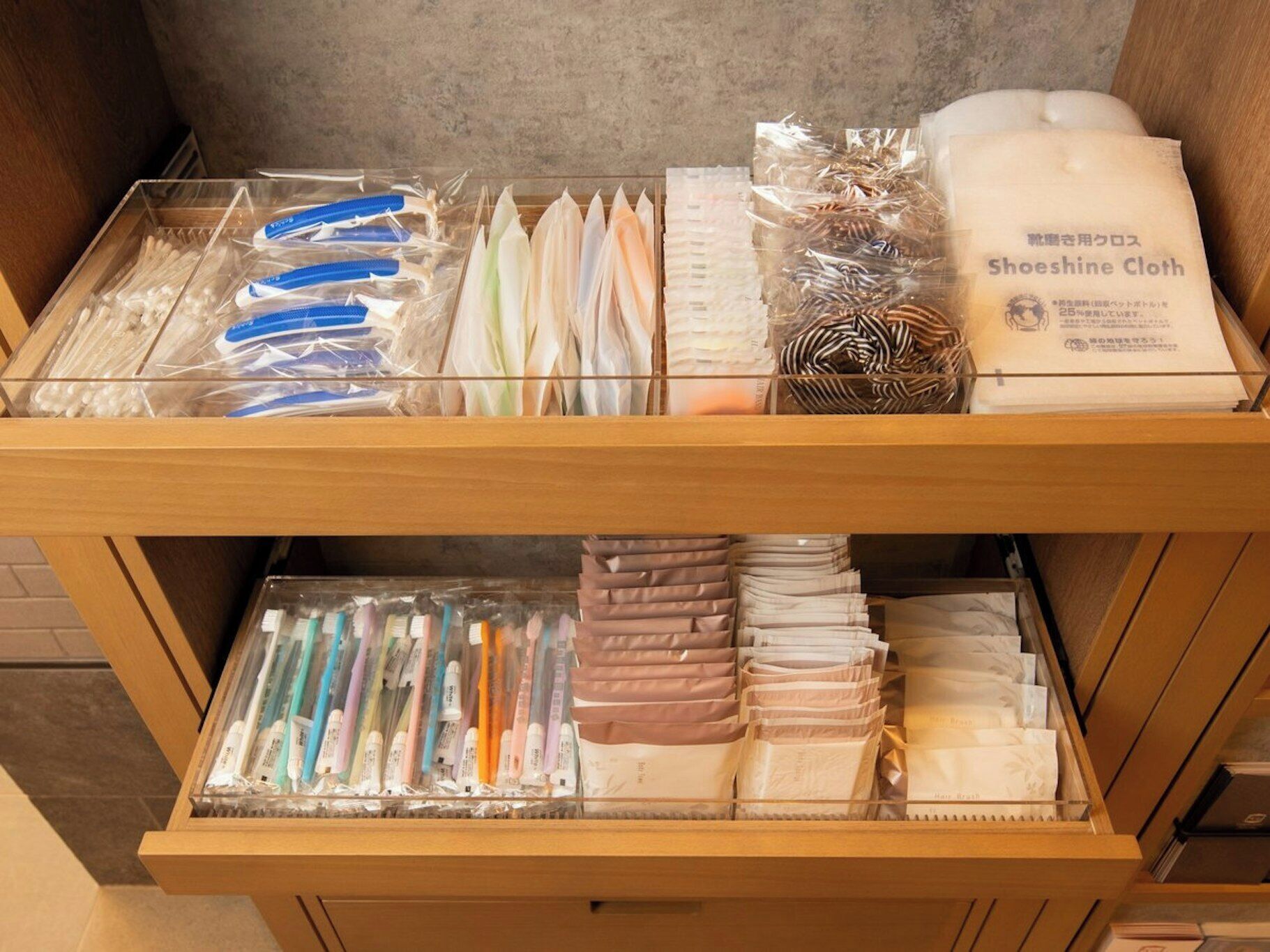 Un cajón con varios objetos, como hilo dental, cepillos de dientes y un paquete de paño para lustrar zapatos.
