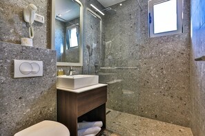 A modern bathroom with a marble wall, a built-in sink, a hairdryer, and a shower. - Bono Hotel (Bečići)
