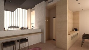 A modern bar area with stools, a counter with bottles, and a view through a window with vertical blinds. - Bono Hotel (Bečići)