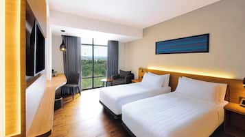 Ein Hotelzimmer mit zwei Betten, einem Schreibtisch, einem Stuhl, einem Fernseher und einem großen Fenster mit Blick.