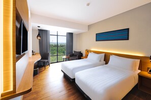 A hotel room with two beds, a TV, a desk, a chair, and a large window with a view. - Harper Kupang (Kupang)