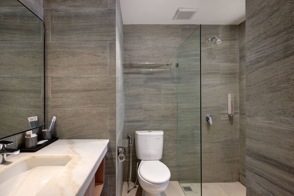 Un baño moderno con ducha acristalada, inodoro blanco y lavamanos de mármol.