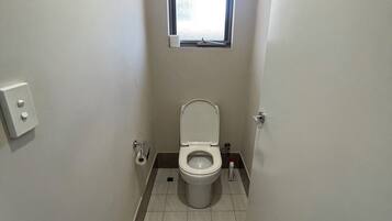 A small, narrow bathroom with a toilet, a window, and a door.