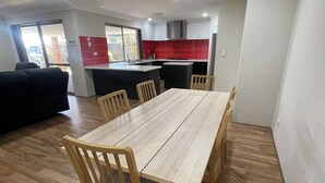 A dining area with a wooden table and chairs, a kitchen with red tiles, and a sliding glass door leading to an outdoor area. - Rehoboth Landsdale WA (Landsdale)