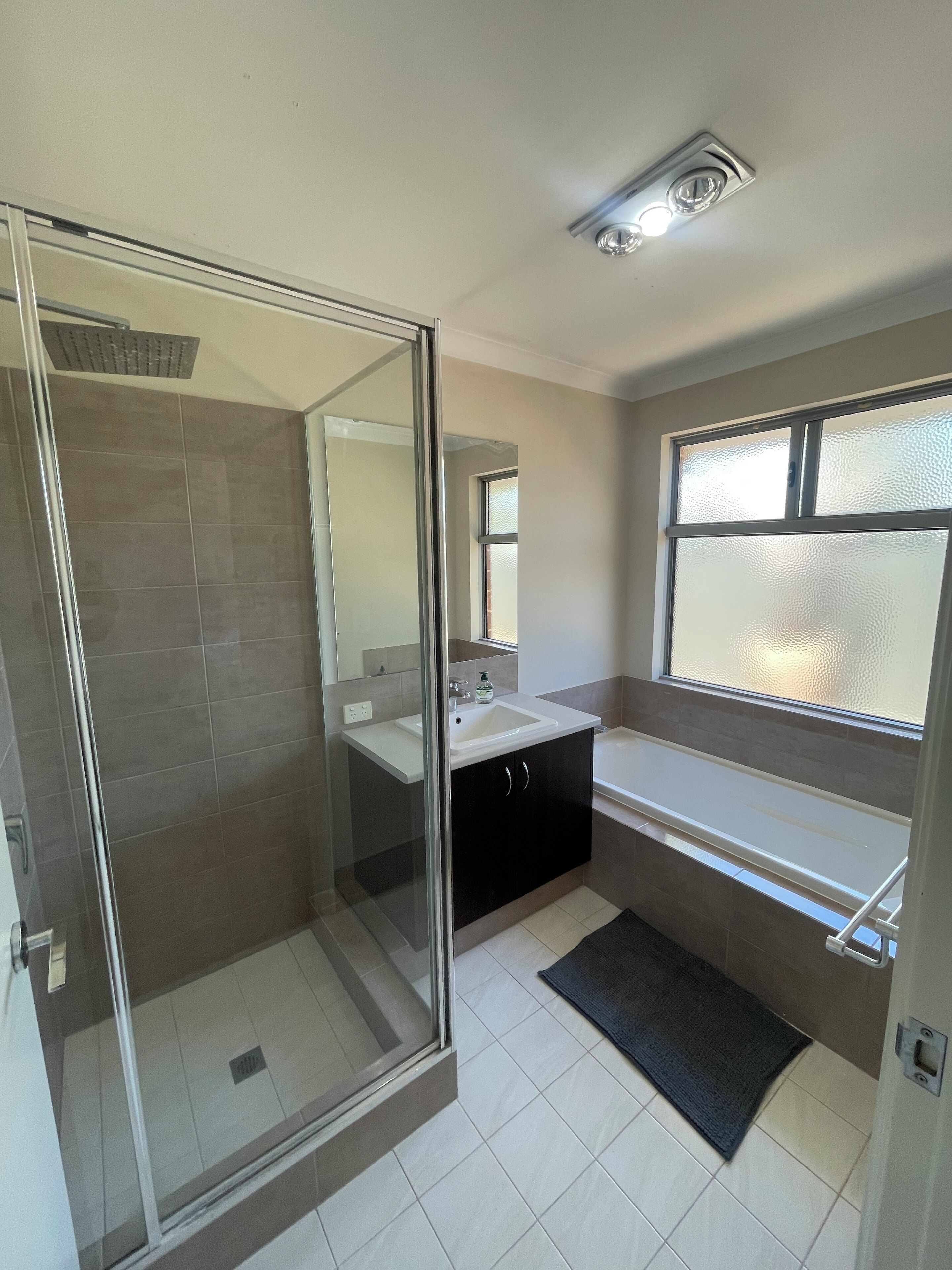 A modern bathroom with a glass shower enclosure, a sink, a vanity, and a bathtub.
