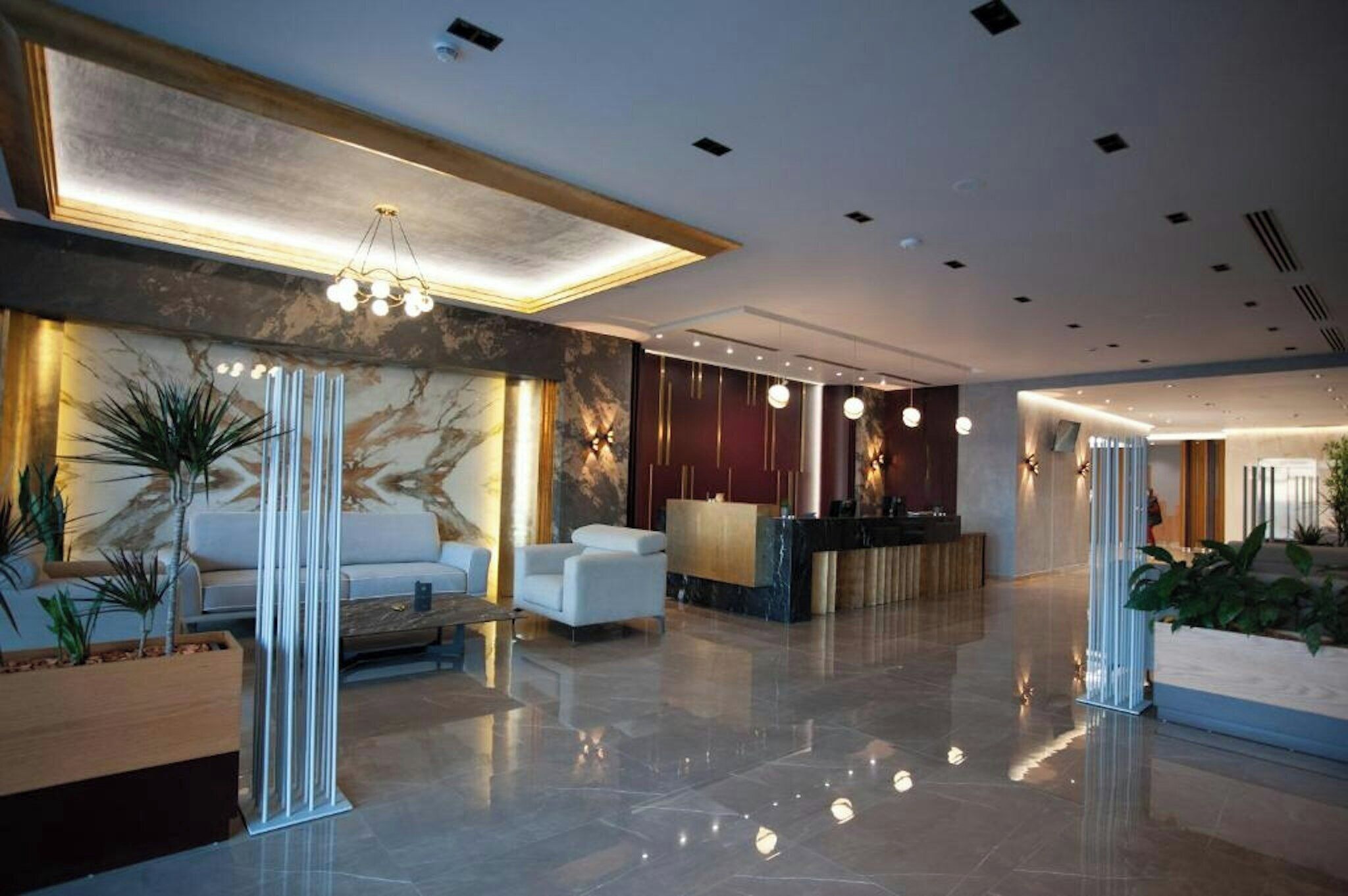 A modern lobby with a reception desk, seating area, and decorative lighting.
