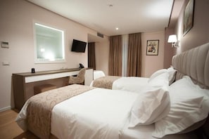 A hotel room with two beds, a desk, a flat-screen TV, and a large window with curtains. - Doanesia Premium Hotel and Spa (Kashar)