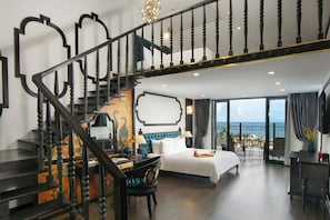 Une chambre d’hôtel avec un grand lit, un bureau, une chaise, un escalier et un balcon avec vue.