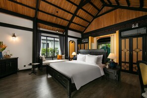 Un dormitorio amplio con una cama grande, una mesita de noche, una silla y un ventanal con cortinas.