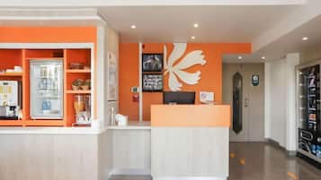 A reception area with a counter, a refrigerator, and a wall-mounted decorative piece.