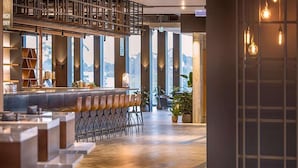 A modern bar area with high ceilings, large windows, and a variety of seating options. - Sage Ringwood (Melbourne)