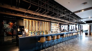 A bar area with a long counter, multiple seating options, and a wine rack in the background. - Sage Ringwood (Melbourne)
