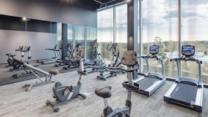 A gym with various cardio machines, large windows, and a view of the outdoors. - Sage Ringwood (Melbourne)