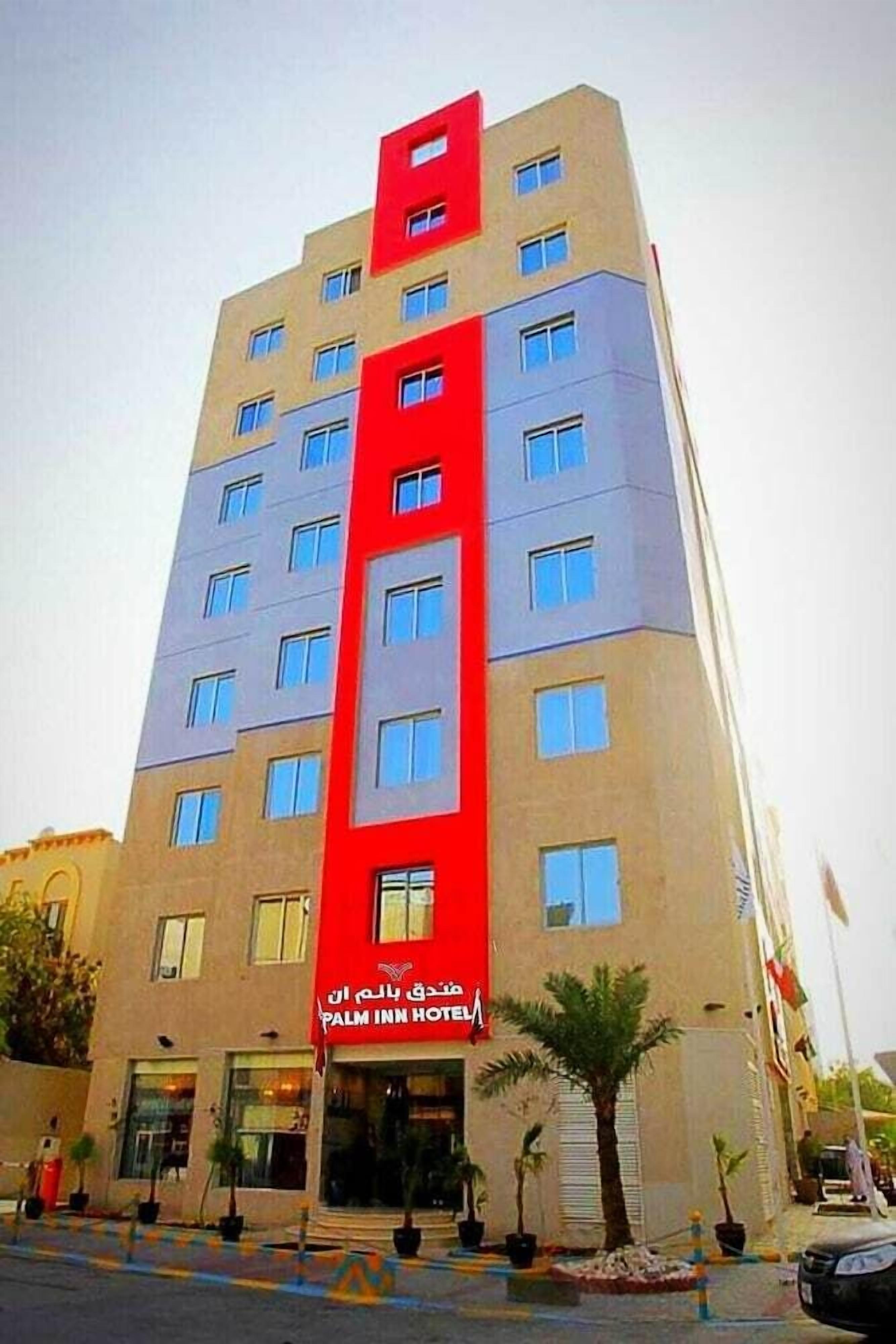 A multi-story hotel with a prominent red vertical stripe and a sign reading "Palm Inn Hotel".