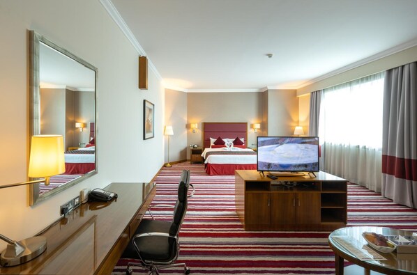 A hotel room with a bed, TV, desk, chair, and a large mirror. - Wonder Palace Hotel (Doha)
