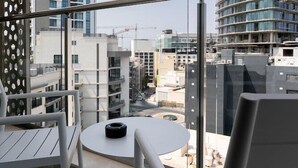 A balcony with a round table and chairs, overlooking a cityscape with modern buildings and construction cranes. - Hotel Mistral St. Julian's (St. Julian's)