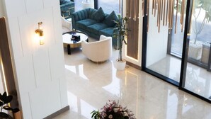 A modern hotel lobby with a green sofa, white armchairs, a coffee table, and a potted plant. - Dream Residence Olaya Khobar (Al Khobar)