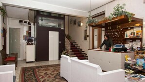 Un hall d’hôtel comprenant un comptoir d’accueil, un escalier et un espace détente avec un tapis à motifs.