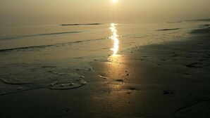 Une plage où le soleil se reflète sur le sable mouillé, créant un chemin de lumière.