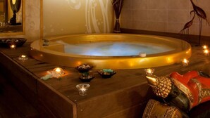 Une salle de spa équipée d’un bain à remous, d’un mur décoratif, d’un miroir et d’une statue.