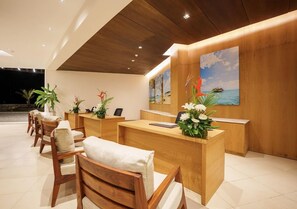 A reception area with wooden reception desk, several chairs, and a painting of a tropical beach scene. - Ocean's Creek (Balaclava)