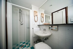 A bathroom with a glass shower enclosure, a white sink, a mirror, and a towel rack. - Hotel Beny (Jesolo)