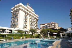 Un hotel con piscina, diversi balconi e cielo sereno.