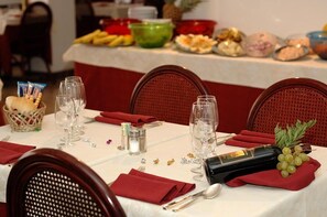 A dining table set with red napkins, wine glasses, and a bottle of wine. - Hotel Beny (Jesolo)