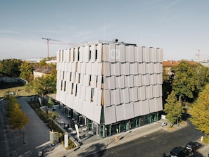 Un edificio moderno con fachada de entramado, ventanas amplias y un patio con mobiliario exterior.