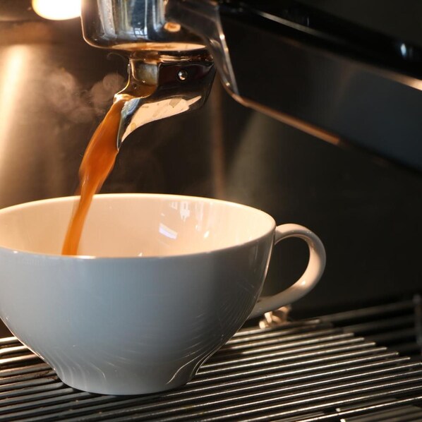 A cup being filled with a liquid, likely coffee, from a machine.