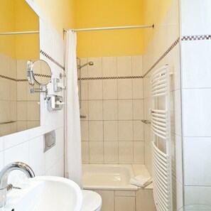 Een badkamer met een wastafel, spiegel, douche en bad.