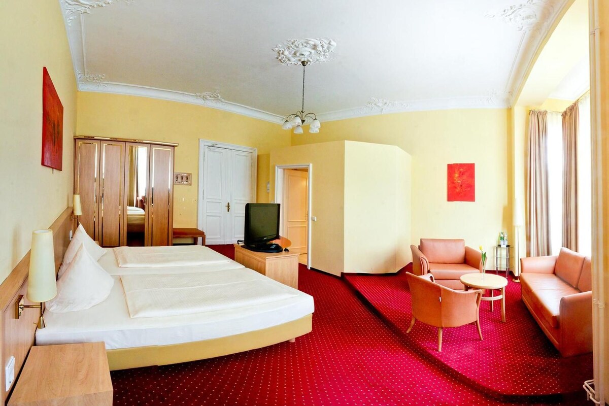 Une chambre d’hôtel comprenant un lit, une télévision, un bureau, une chaise et un canapé.