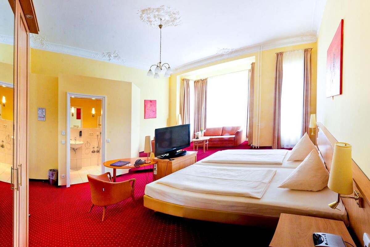 Een hotelkamer met een bed, een bureau, een televisie, een bank en een badkamer.