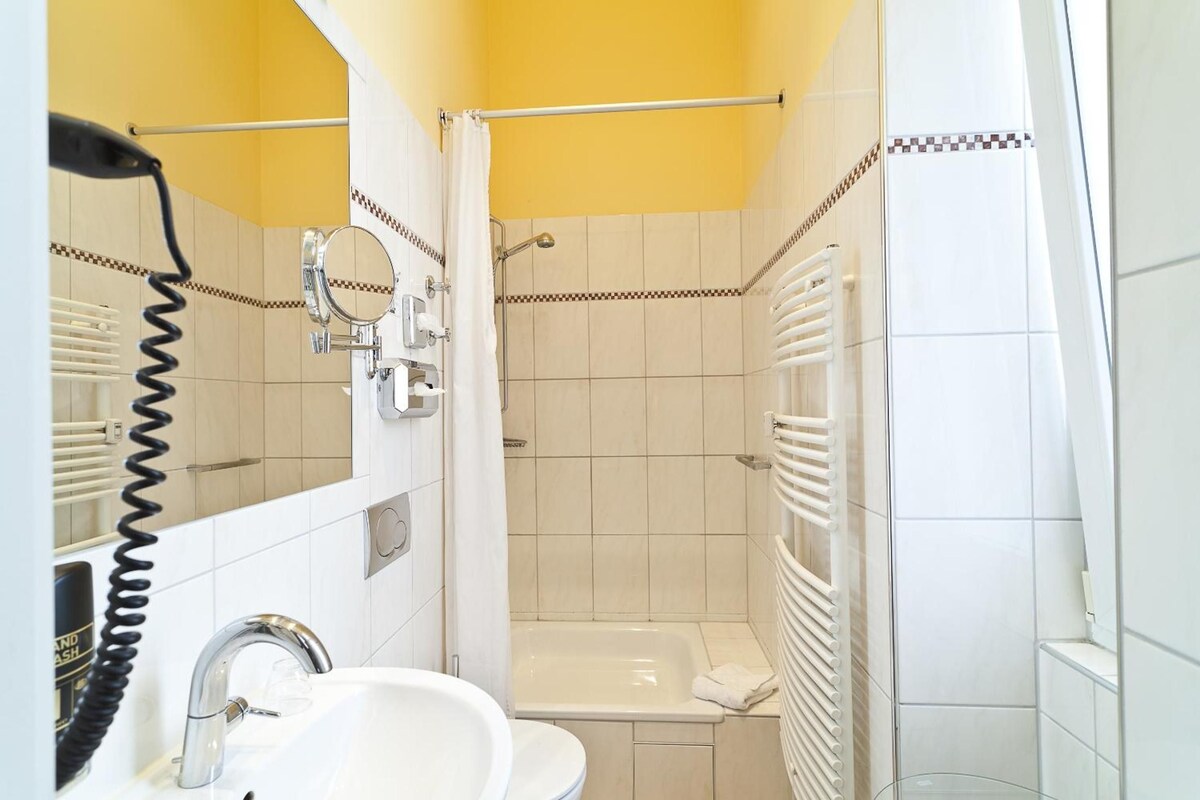Een badkamer met een wit wastafel, een spiegel, een douche en een bad.